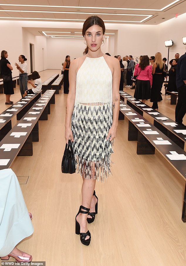 Beautiful: Rainey Qualley looked beautiful in a sleeveless top with white fringes that showed off a hint of her stomach, which she paired with a knee-length, black and white skirt with zigzag pattern and fringe at the hem