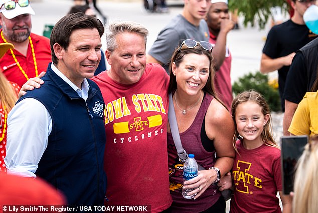 Florida's governor takes a photo with supporters at an Iowa State Wrestling tailgate before the match started