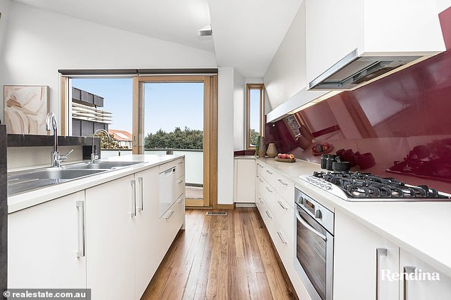 The kitchen is equipped with a central island bench and hardwood floors