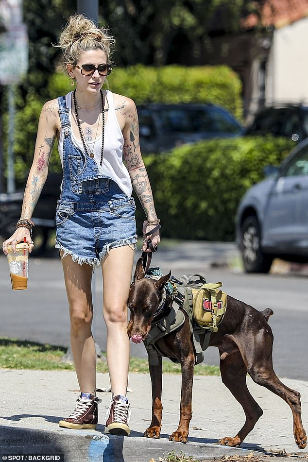 Rocker chic: The singer-songwriter kept it rocker cool in the fashion department with cut-off denim overalls, a white tank top and brown high-top sneakers