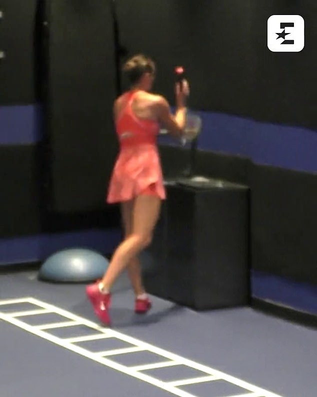 After smashing her racket four times on the hard floor, Sabalenka places it in a container