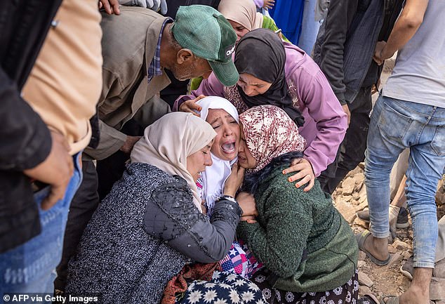 A woman cries and is comforted by family as volunteers recover the body of a relative from collapsed houses in the village of N'Tala, central Morocco, September 10