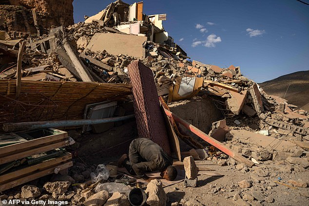 A volunteer prays near the rubble of collapsed buildings in the village of Imi N'Tala