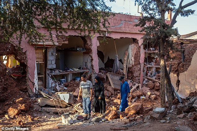 People walk past a partially collapsed building in Ouirgane, Morocco on September 10, 2023