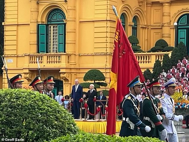 Former Secretary of State John Kerry stands behind President Joe Biden (left) and Vietnam Communist Party Secretary General Nguyen Phu Trong (right).  Kerry and Biden will pay tribute to Senator John McCain in Hanoi on Monday