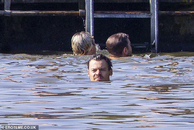 Having fun: Harry swept back his long, wet locks as his face cooled in the water