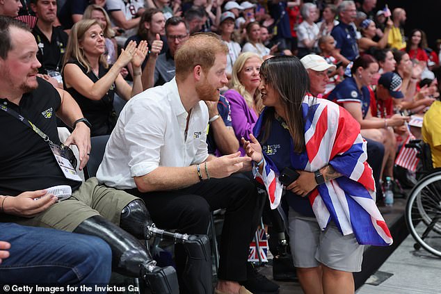 Prince Harry sat front row for the wheelchair rugby final between Team USA and Team UK at the Invictus Games.  He talks to a fan draped in a Union Flag