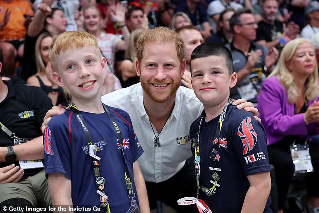 Harry smiles and poses with two young people during the final.  A large number of British supporters waved flags and tried to shout down their rivals, who were waving the stars and stripes flag