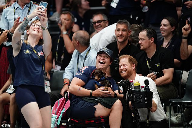 Another British fan takes a selfie as a friend sits next to a smiling Harry holding his pet