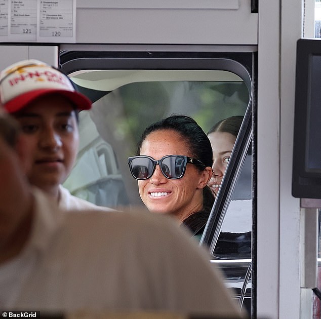 The Duchess of Sussex, 42, grinned as she waited for her food at In-N-Out behind the wheel of her $140,000 black Range Rover, near the couple's $14.6 million home in Montecito, before she went to the airport.