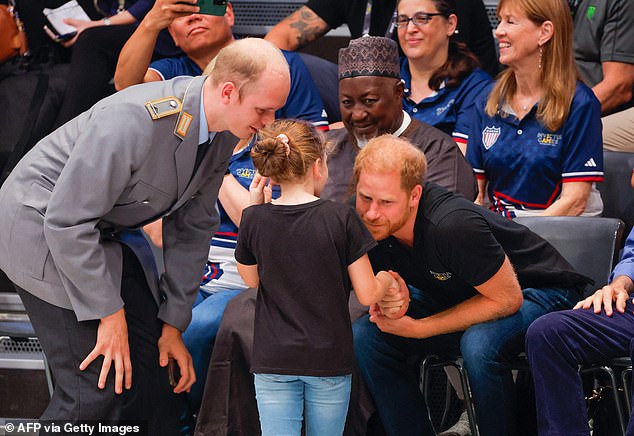 The Duke of Sussex chats to a girl while attending the wheelchair rugby match