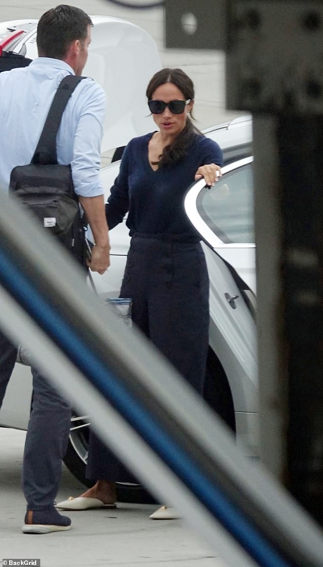 Meghan and her bodyguard as they left their luxury BMW at Los Angeles airport last night