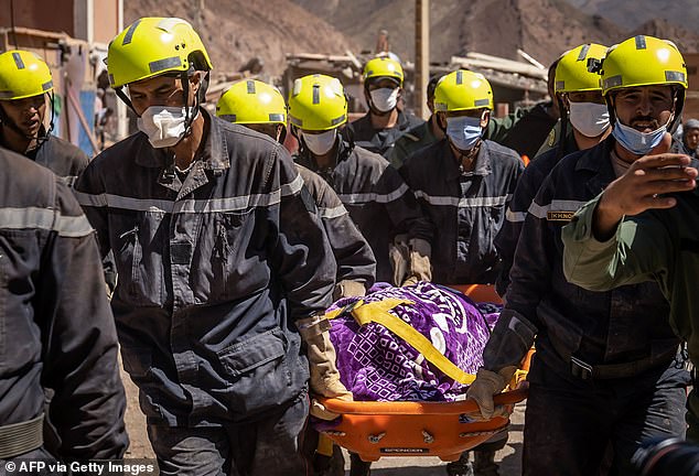 Moroccan rescuers pull a body from the rubble in the village of Talat N'Yacoub in al-Haouz province