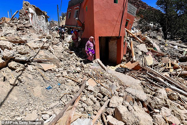 Women react as they walk through the rubble of the village of Imoulas in Taroudant province