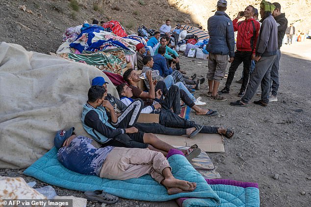 People wait as emergency workers open a road to their village in the mountainous Tizi N'Test area, Taroudant province