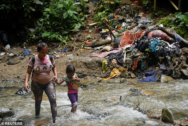 A migrant walks with a child as they continue their journey with others toward the U.S. border, in Acandi, Colombia, July 9, 2023