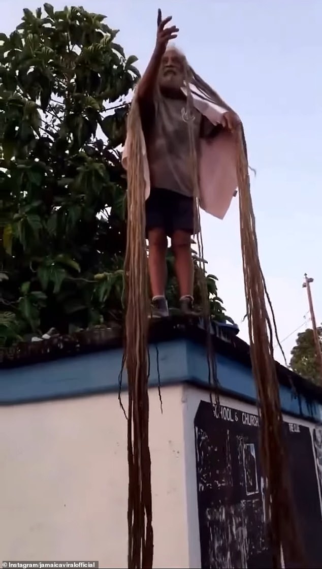 The person filming him asked him questions as he untangled the strands of hair hanging halfway down the side of the building