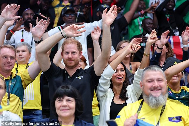 Prince Harry and Meghan Markle wave their hands during the wheelchair basketball match today