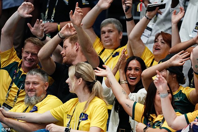 Prince Harry and Meghan Markle wave their hands during the wheelchair basketball match today