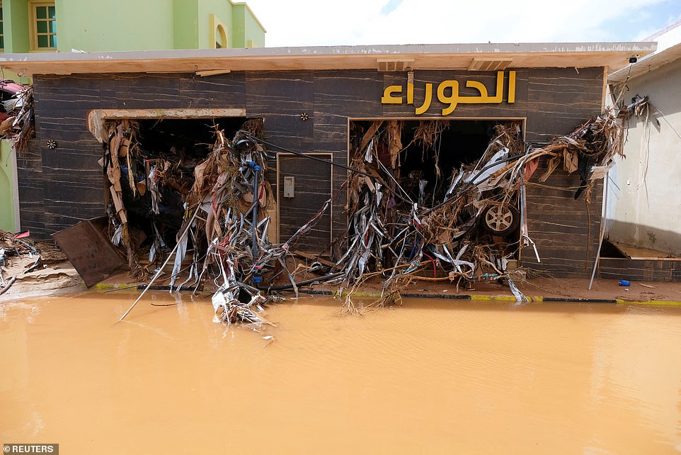 A flooded road in Derna.  Car wheels and other debris are scattered across a destroyed building