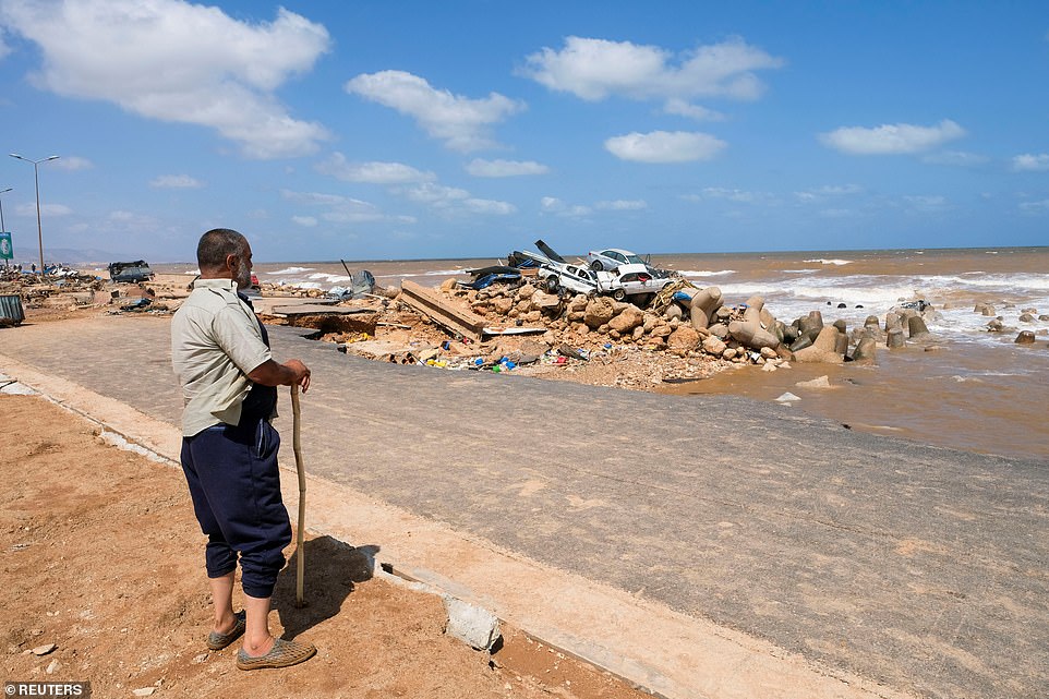 A resident looks at the pile of damaged cars stranded on the Derna coastline after a powerful storm and heavy rain.