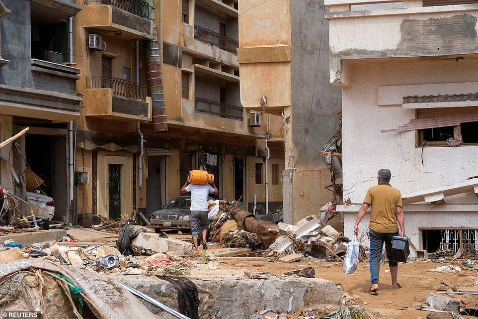 Men carry supplies through the ruins of the city, with rubble littering the streets after this week's powerful storm and flooding