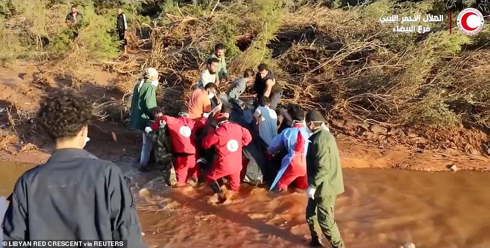 Libyan Red Crescent volunteers wade through high tides as they take part in a rescue operation