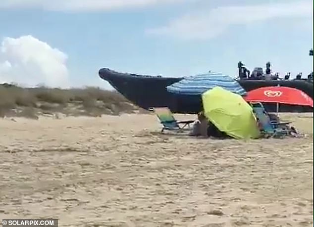 The men were filmed walking at high speed towards the sand, narrowly missing the parasols that sunbathers had rushed away from as they rammed them into the dunes