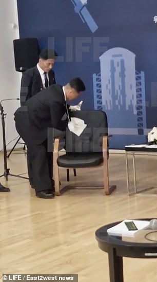 Footage first showed a man wearing white gloves and a dark suit wiping down the black chair with a white cloth before the two leaders sat down for the meeting.