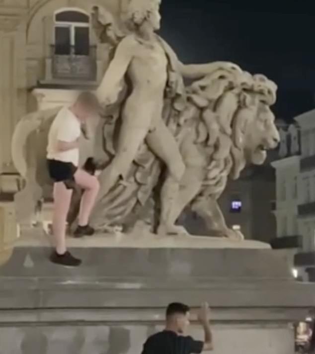 Amazed crowds watched as he climbed onto the sculpture, which depicts a lion and a man holding a torch