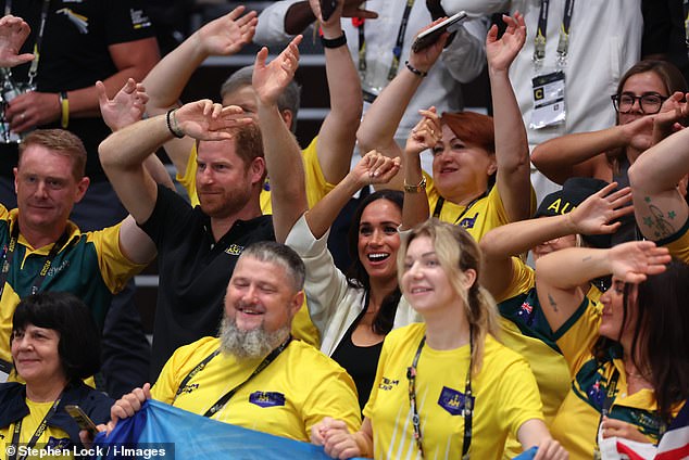 Prince Harry and Meghan Markle wave their hands during the wheelchair basketball match today