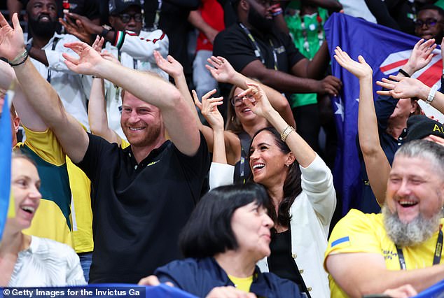 Prince Harry and Meghan Markle wave their hands during the wheelchair basketball match today