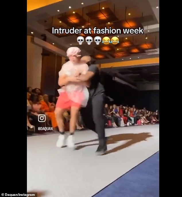 At the end of the ramp, the security guard grabs him and drags him off the runway, leaving the audience shocked.