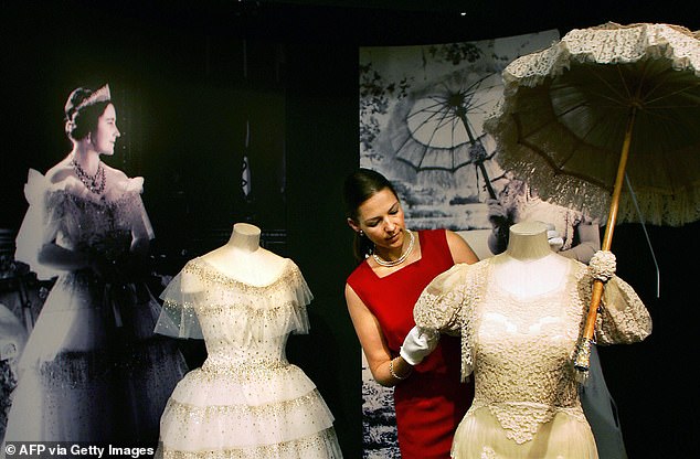 Caroline de Guitaut, assistant curator of works of art, adjusts the 'day dress' during the preview of Queen Elizabeth's white wardrobe, Paris 1938