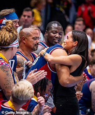 Meghan appears to pat one of the players on the back as she meets the team