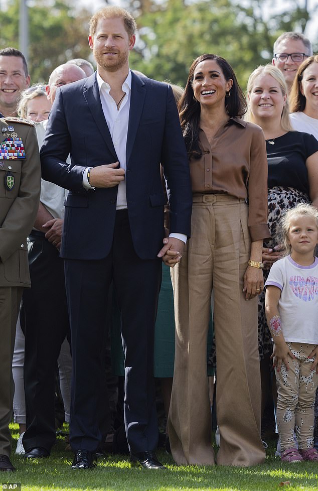 Meghan Markle opted for another muted outfit today as she wore a brown silk shirt and trousers to join Prince Harry at the Invictus Games