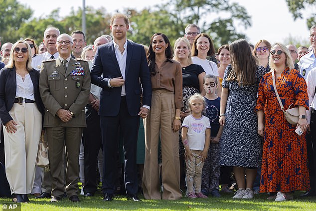 She added her £5,000 Cartier love bracelet to the look as she walked hand in hand with Prince Harry