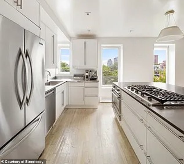 The open kitchen has a large cooking island with Caesarstone top, stainless worktop with deep integrated sink, dishwasher and Kitchenaid refrigerator