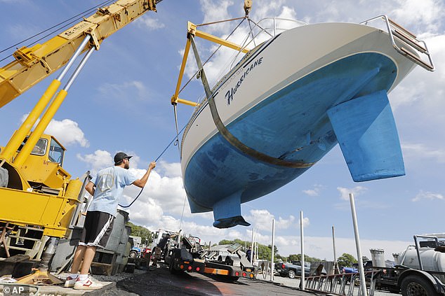 Crews from Davis & Tripp Marina and Boat Yard pull a sailboat named Hurricane from the waters of Padanaram Harbor in Dartmouth, Massachusetts