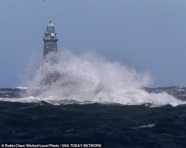 Waves crash in front of the Minot Lighthouse off the coast of Minot Beach in Scituate, Massachusetts