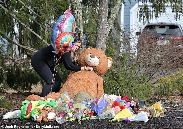 A well-wisher visits the makeshift memorial that grew in front of the family's home in Duxbury