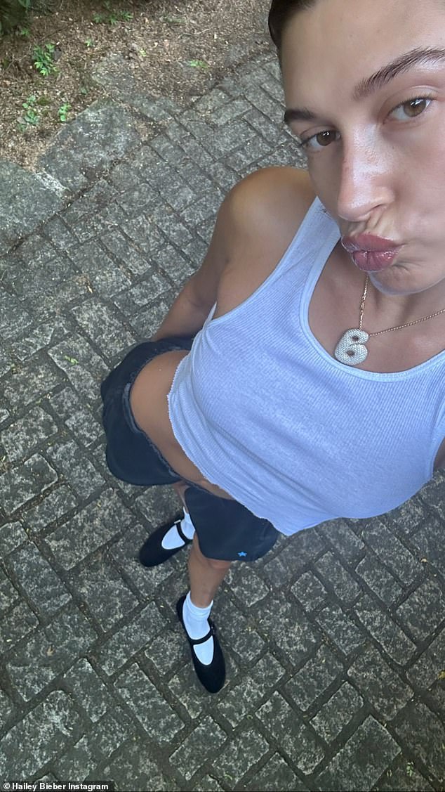 Chic schoolgirl: Hailey showed off her abs in several looks and pursed her lips in another selfie, where she wore a white tank top, gray shorts and black Mary Jane shoes with white socks