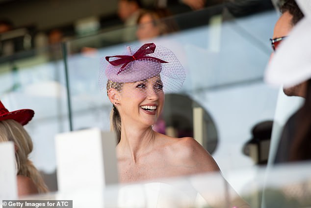 She paired the split-hem dress with a pair of strappy heels and clutched a pastel purple clutch in one hand to match her extravagant purple fascinator.