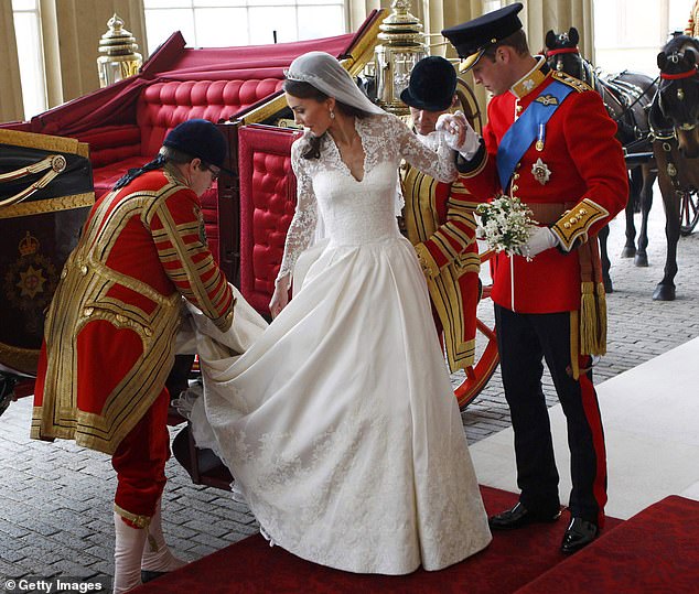 Kate is helped with her train by a footman as she and Prince William arrive at Buckingham Palace after the ceremony