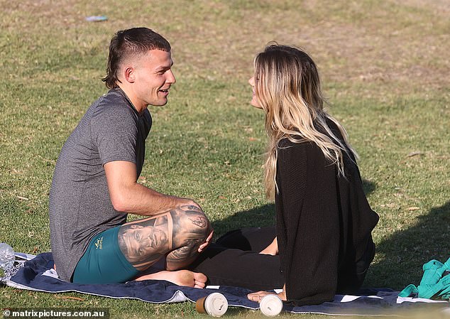 Lounging on a towel on the grass, the couple cuddled close