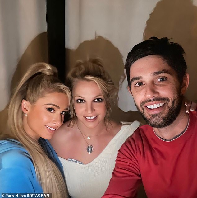 Paris Hilton poses in a snap with Britney Spears and Cade Hudson, making Spears' necklace appear to be attached to only one chain