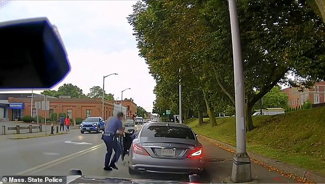 The other officers try to pull his partner out of the vehicle as the driver drives away