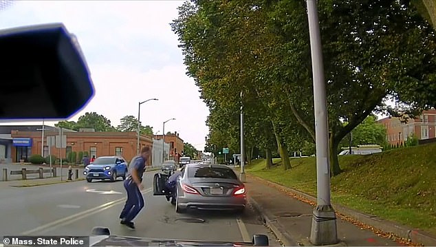 The officer bravely clings to the car as the driver drives away from the scene