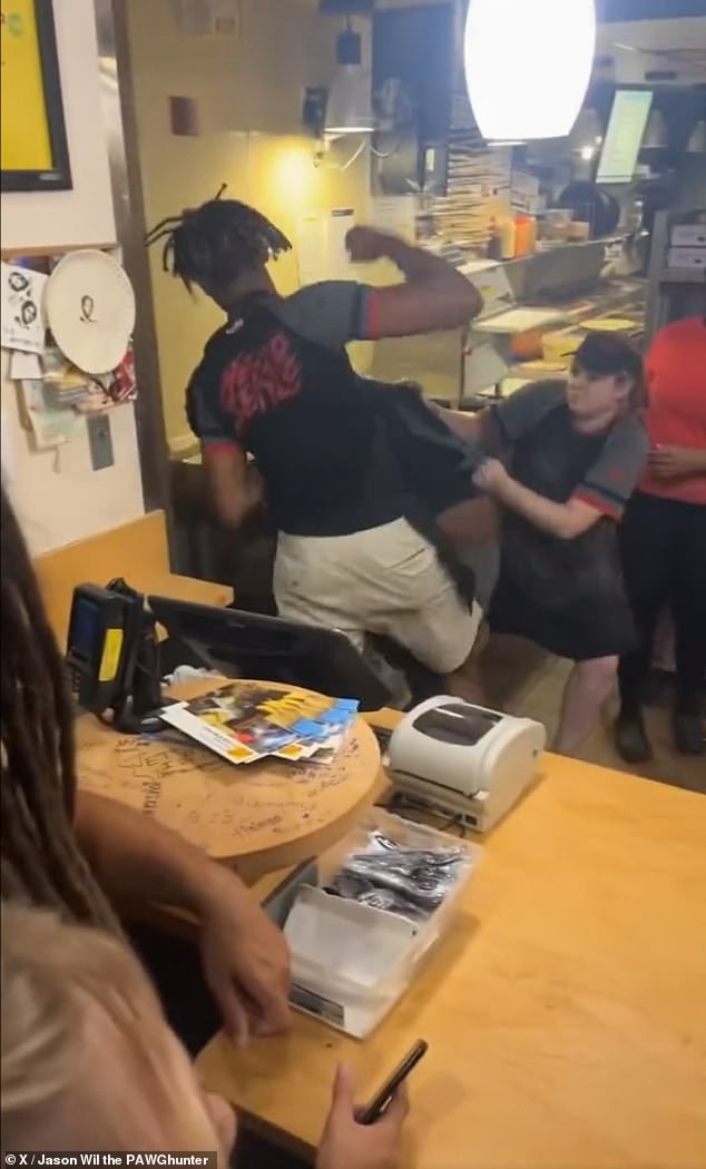 An employee can be seen clenching his fists as the unidentified man fights another employee on the ground