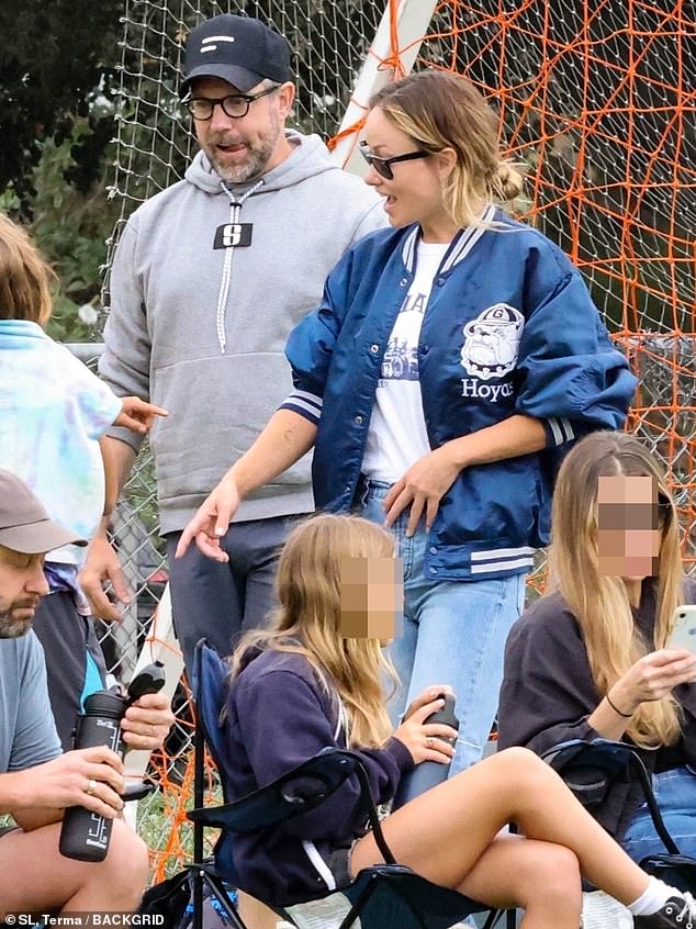 Taking it easy: Wilde opted for a white graphic T-shirt worn under a puffy blue varsity jacket during the match